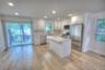 Kitchen featuring shaker-style cabinetry, a central island with a stone-finish countertop, stainless steel appliances, and wood-finish flooring