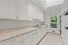 Kitchen featuring white cabinetry, stone countertops, integrated double wall ovens, recessed lighting, and a skylight