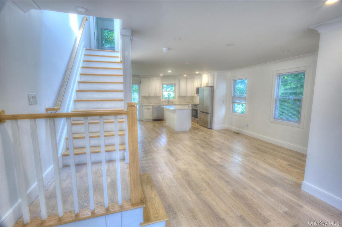 Open-concept interior featuring wood-finish flooring, recessed lighting, and a kitchen equipped with a center island and stainless steel appliances, a
