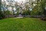 Expansive backyard featuring a level lawn, mature trees, wood privacy fencing, a cement patio area large enough to accommodate a 2 car garage and buil