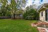 Private backyard featuring a level lawn, mature trees, wood privacy fencing, and a brick-stepped entrance