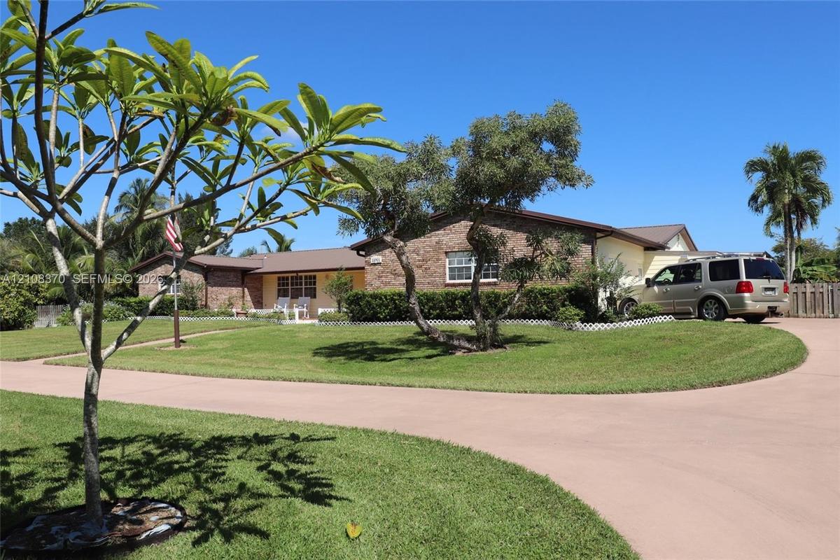 Single-story residence featuring a brick and siding exterior, expansive lawn, mature landscaping, and a concrete driveway