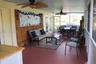 Screened-in porch featuring painted concrete flooring, bamboo-paneled wall accent, dual ceiling fans, and double-door entry