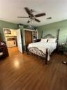Room featuring wood-finish flooring, a ceiling fan with integrated lighting, and a reach-in closet with wood-finish sliding doors