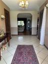 Foyer featuring diagonal-set ceramic tile flooring, arched architectural detailing, multi-arm crystal chandelier, and louvered-style closet doors