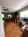 Wood-finish flooring, multi-blade ceiling fan with integrated lighting, and dual windows with horizontal blinds