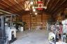 Expansive metal-framed workshop featuring exposed truss construction, high ceilings, concrete flooring, plywood wall paneling, and integrated fluoresc
