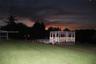 Backyard area featuring an elevated wooden gazebo, an above-ground pool, and a manicured lawn