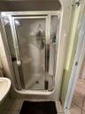 Shower enclosure featuring a chrome-framed glass door, integrated molded shower surround, and a wall-mounted shower fixture