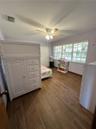 Wood-finish flooring, multi-pane window with grid pattern, and ceiling fan with integrated lighting