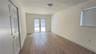 Interior space featuring light-toned wood-finish flooring, dual-panel closet doors, white walls, and French doors leading to a paved patio area