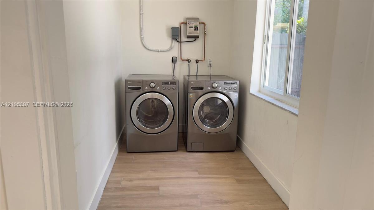 Dedicated laundry space featuring wood-finish flooring and a single-hung window