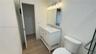 Bathroom vanity featuring stone-finish countertop, integrated sink, and white cabinetry, accompanied by a rectangular mirror, five-light fixture, and 