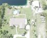 Waterfront property featuring a detached garage, a circular above-ground pool, a concrete driveway, and expansive lawn space
