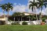 Exterior space featuring a large screened-in porch, white picket fencing, mature palm trees, and a built-in outdoor cooking station