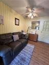 Vertical wood-plank wall paneling, light-toned wood-finish flooring, ceiling fan with integrated multi-light fixture, and a multi-pane door with X-pat