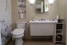 Wall-mounted sink with integrated storage, full-height stone-patterned tile wall, recessed shelving, and dual wall-mounted light fixtures