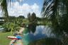 Waterfront property featuring a private shoreline, expansive grassy lawn, and mature palm trees