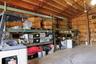 Industrial workspace featuring high-clearance exposed truss ceilings, concrete flooring, and built-in steel warehouse shelving units