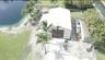 Detached metal workshop featuring dual sliding doors, a white exterior finish, concrete driveway, and direct water frontage on a landscaped lot