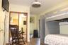 Wood-finish flooring, vertical panel wall detailing, mirrored sliding closet doors with built-in overhead storage, and a ceiling-mounted light fixture