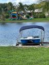 Waterfront property featuring a private wooden dock and manicured lawn with mature palm trees