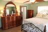 Room featuring wood-finish flooring, a ceiling fan, and louvered closet doors