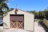 Outbuilding featuring vertical metal siding, dual cross-buck doors, a decorative metal horse silhouette, and a weather vane