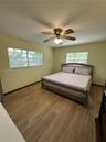 Interior space featuring wood-finish tile flooring, two windows with horizontal blinds, and a multi-blade ceiling fan with integrated lighting