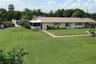 Expansive lawn with mature trees, metal roofing, and multiple screened-in enclosures