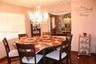Dining area featuring wood-finish flooring, a multi-tiered crystal chandelier, and large window with horizontal blinds