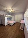 Wood-finish plank flooring, ceiling fan with integrated light fixture, and dual-panel sliding closet doors