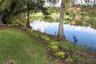 Waterfront lot featuring mature trees, landscaped border plantings, and expansive lawn