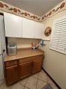 Custom cabinetry featuring white upper storage and wood-finish lower base cabinets with stone-finish countertops and white plantation shutters