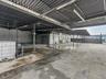 Covered exterior space featuring a expansive concrete foundation, corrugated metal roofing, integrated structural steel support columns, and overhead 