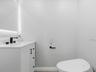 White shaker-style vanity with stone-composite countertop, integrated sink, matte black widespread faucet, and integrated backlighting