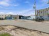 Industrial exterior featuring concrete block construction, paved asphalt lot, and perimeter security fencing with gated access