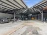 Expansive covered workspace featuring high-clearance steel beam construction, corrugated metal roofing, integrated ceiling-mounted lighting, and concr