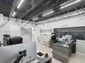Industrial-style interior featuring an exposed black ceiling with steel trusses, recessed linear lighting, light wood-finish flooring, and a large int