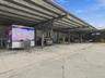 Expansive industrial-style covered parking area featuring a high-clearance metal roof, steel structural support beams, and a concrete slab foundation