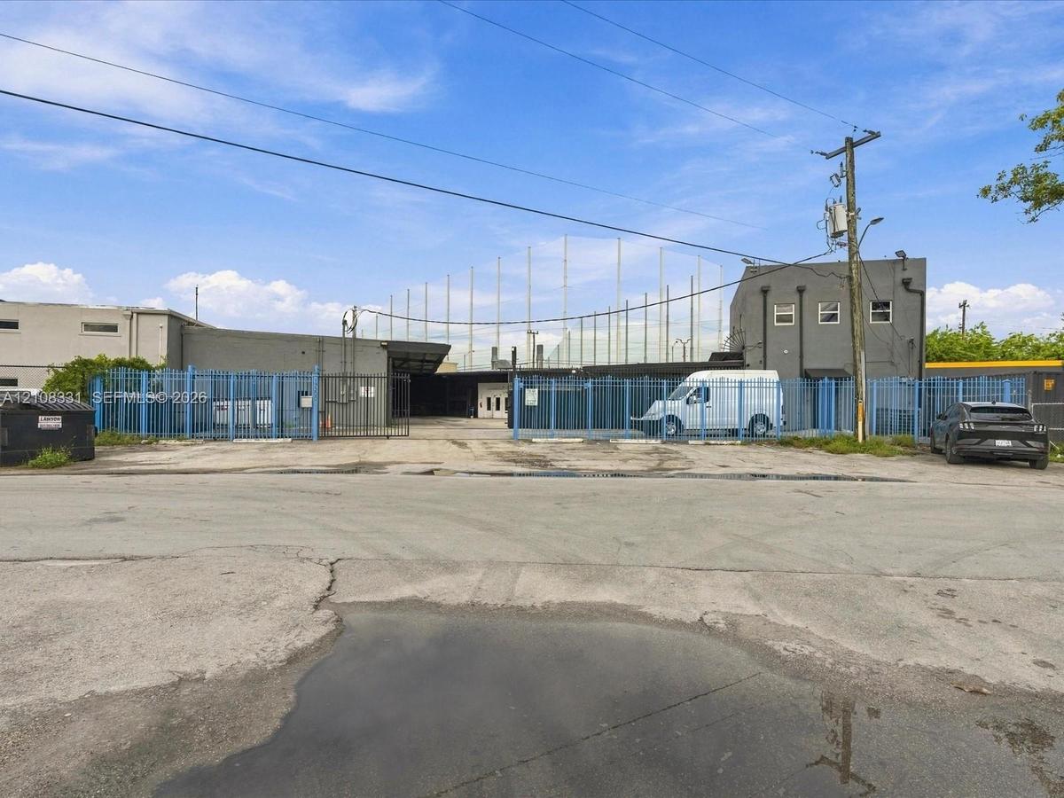 Commercial property featuring a gated paved exterior, perimeter fencing, and concrete foundation