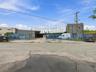 Commercial property featuring a gated paved exterior, perimeter fencing, and concrete foundation