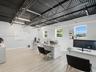 Open-concept space featuring wood-finish flooring, exposed industrial ceiling trusses, and recessed linear lighting