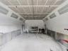 Enclosed professional paint booth featuring integrated overhead fluorescent lighting, paneled ceiling, and concrete flooring