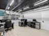 Industrial-style interior featuring an exposed black metal ceiling, linear LED light fixtures, wood-finish flooring, and expansive windows