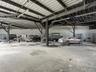 Expansive industrial-style garage featuring exposed steel beam framing, a high-clearance metal roof, concrete flooring, and overhead lighting fixtures