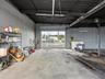 Open-bay warehouse structure featuring exposed metal ceiling joists, masonry walls, concrete flooring, and an oversized roll-up garage door