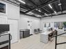 Open-concept workspace featuring industrial-style exposed black ceiling, wood-finish flooring, linear LED lighting, and built-in cabinetry with a mult