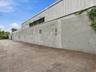 Industrial exterior featuring a concrete masonry unit wall, corrugated metal siding, and a paved asphalt surface