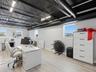 Open-concept room featuring a corrugated metal ceiling with exposed black industrial ducting, wood-finish flooring, and multiple exterior-facing windo